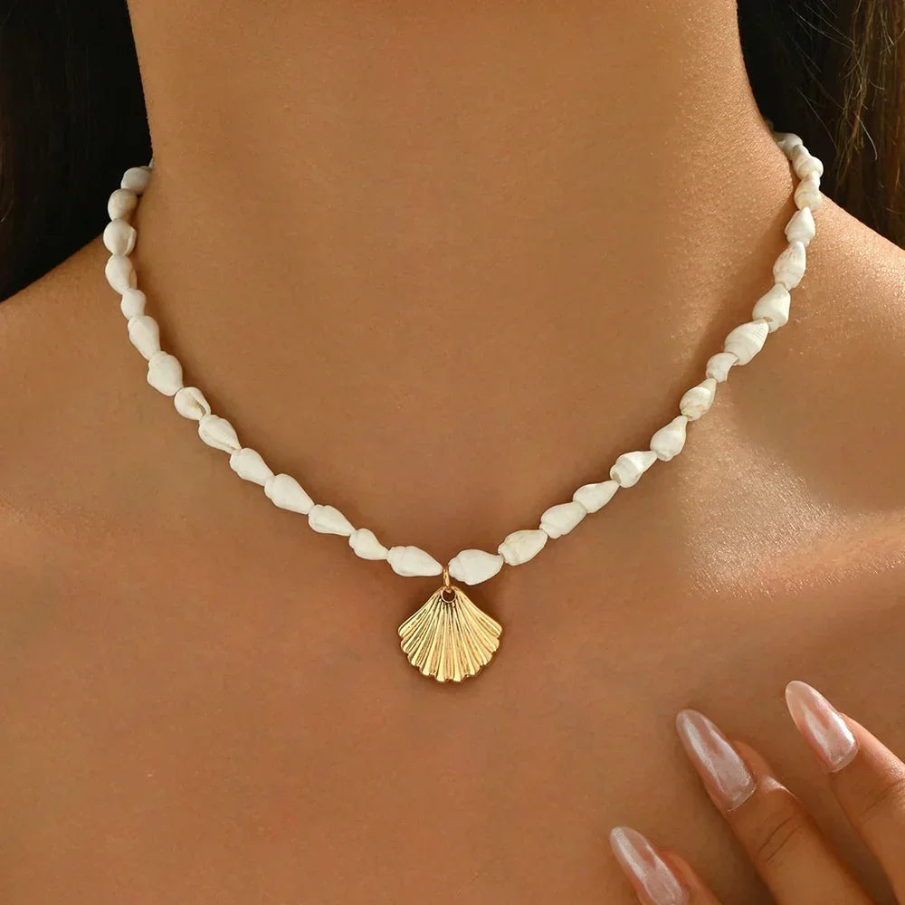 Rovelli white beaded necklace with gold shell pendant, worn close to the neck