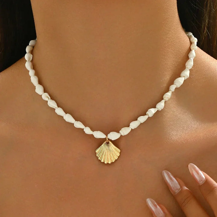 Rovelli white beaded necklace with gold shell pendant, worn close to the neck