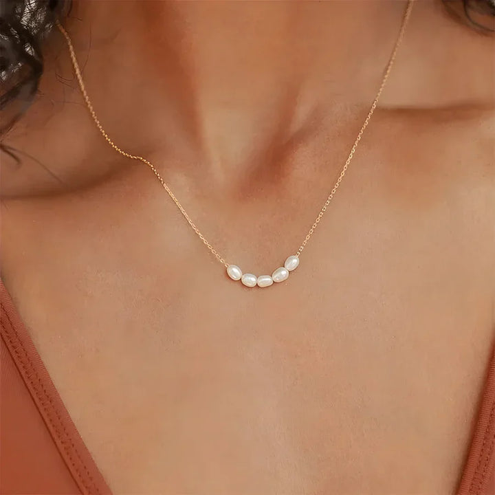 Gold chain necklace with five white pearls on a woman's neck, Rovelli jewelry
