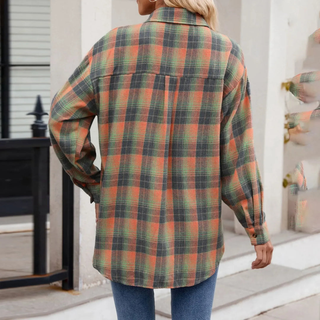 A person wearing an oversized fit, long-sleeve plaid button-down shirt in shades of orange, green, and black paired with blue jeans, standing outdoors with their back facing the camera.