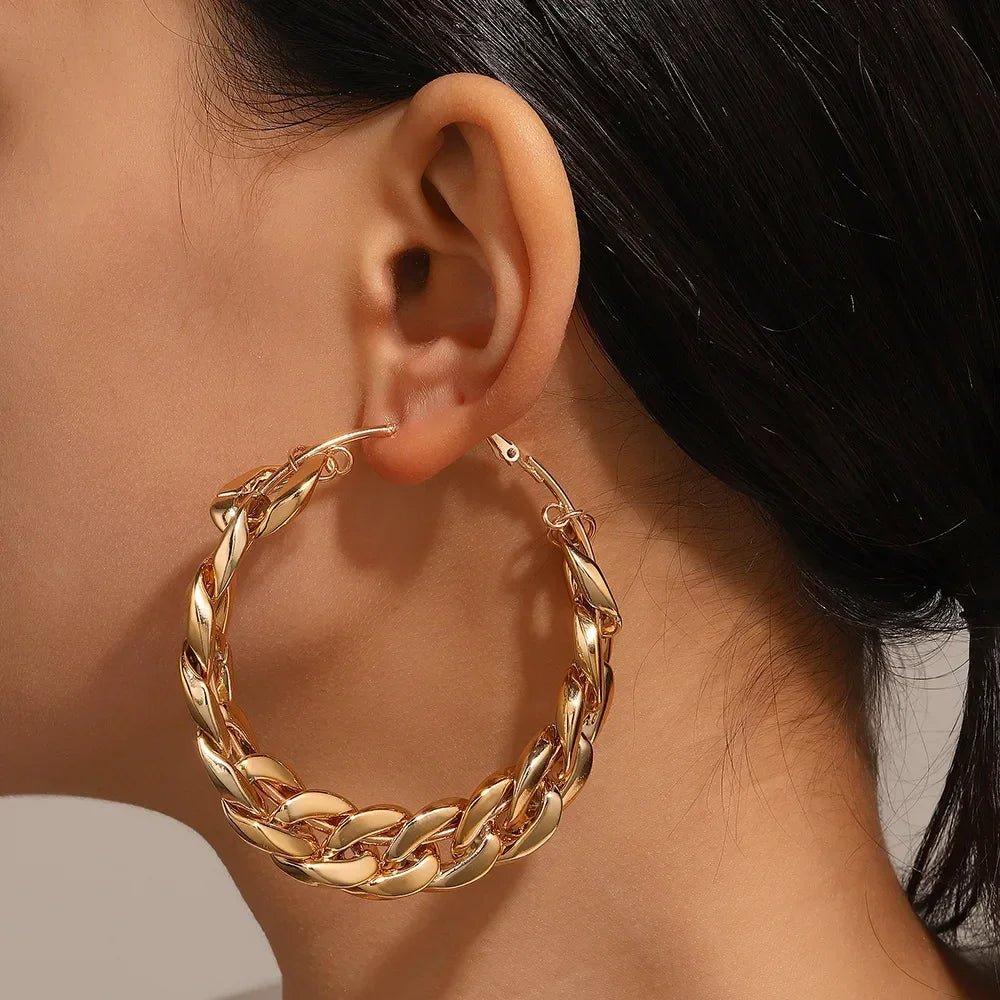 Close-up of a woman wearing a chunky gold chain hoop earring, Rovelli jewelry