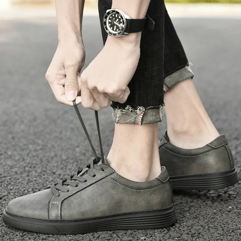 Rovelli gray casual sneakers being tied, worn with cuffed jeans on outdoor pavement