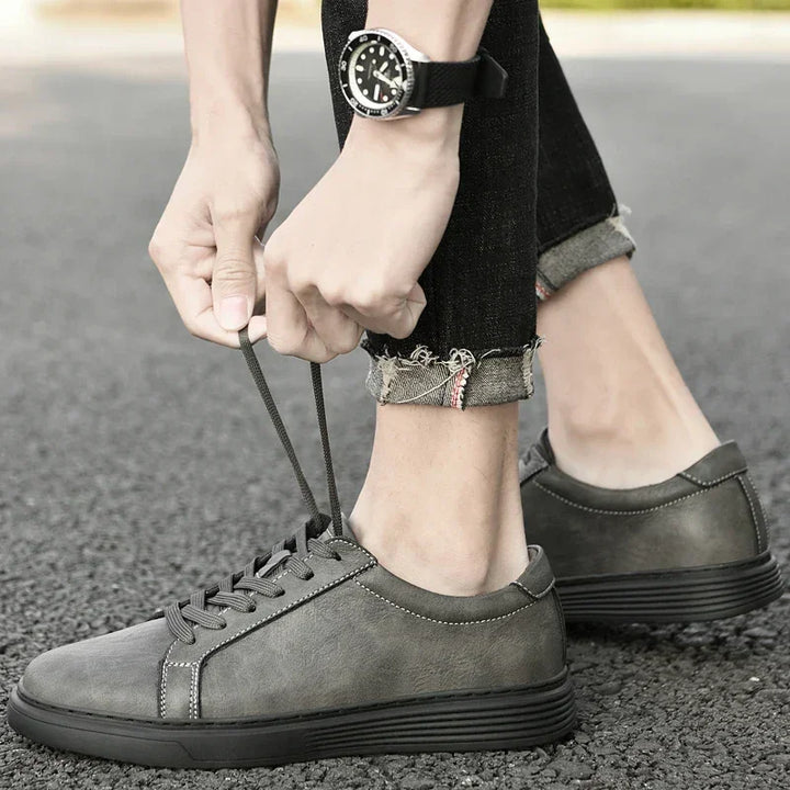Rovelli gray casual sneakers being tied, worn with cuffed jeans on outdoor pavement