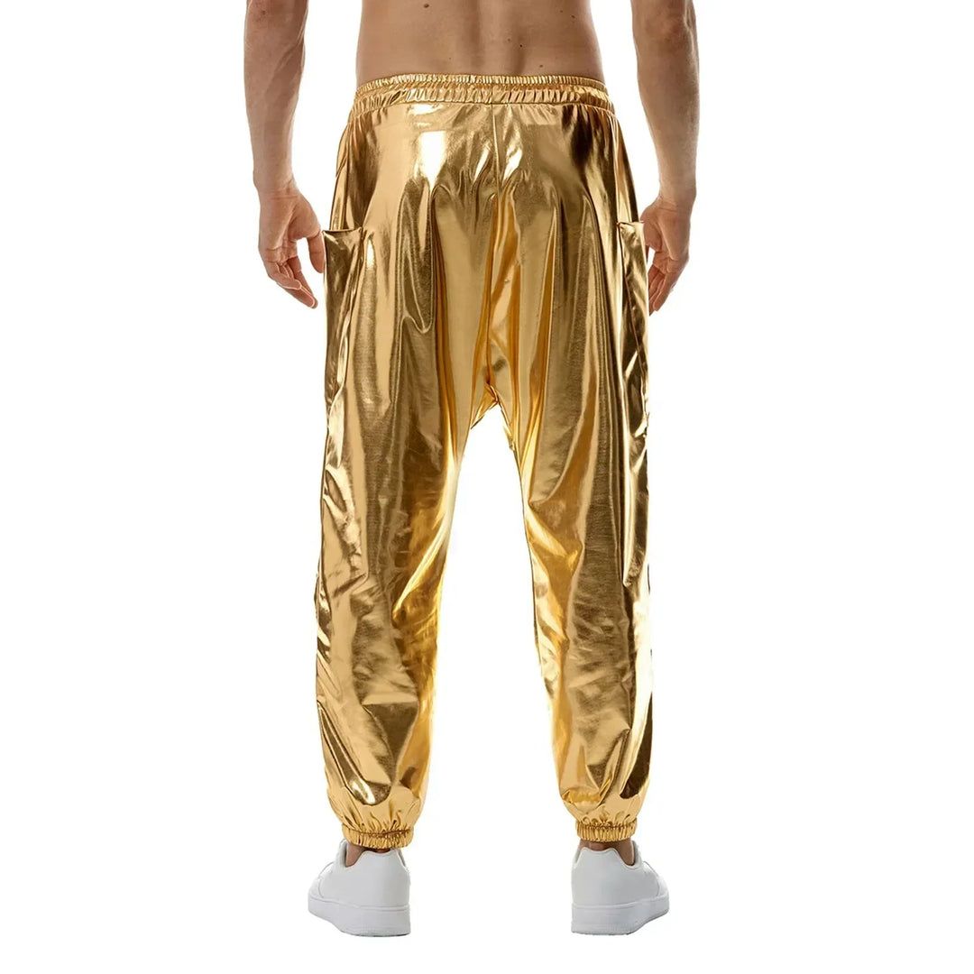 A person wearing shiny gold harem pants made from lightweight metallic fabric and white sneakers is seen from the back against a plain white background. The pants feature an elastic waistband and cuffs.