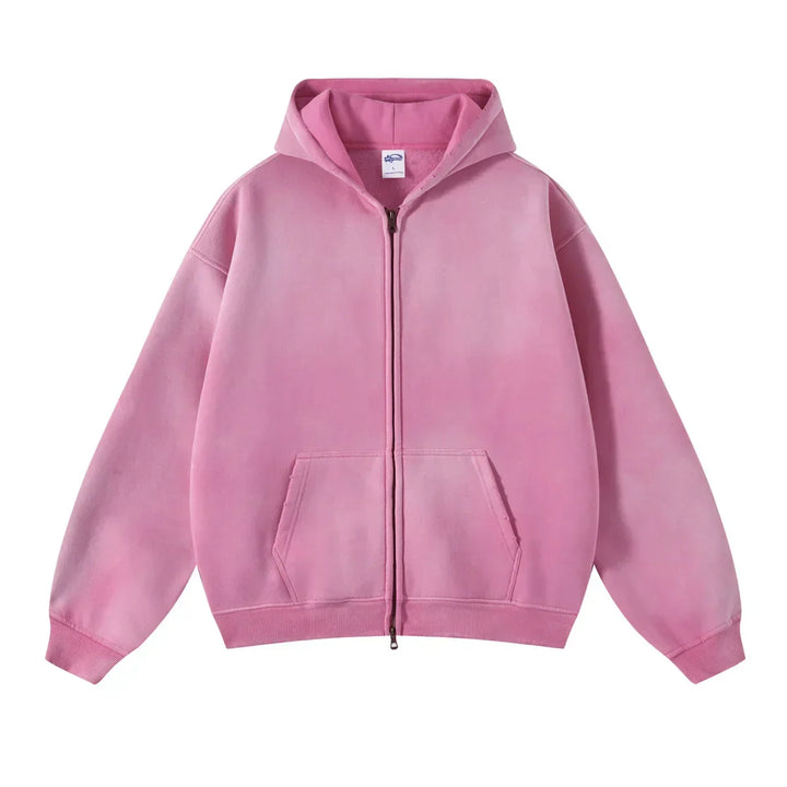 A pink zip-up hoodie with a relaxed fit, front pockets, and ribbed cuffs and hem features thickened fabric for extra warmth, displayed against a white background.