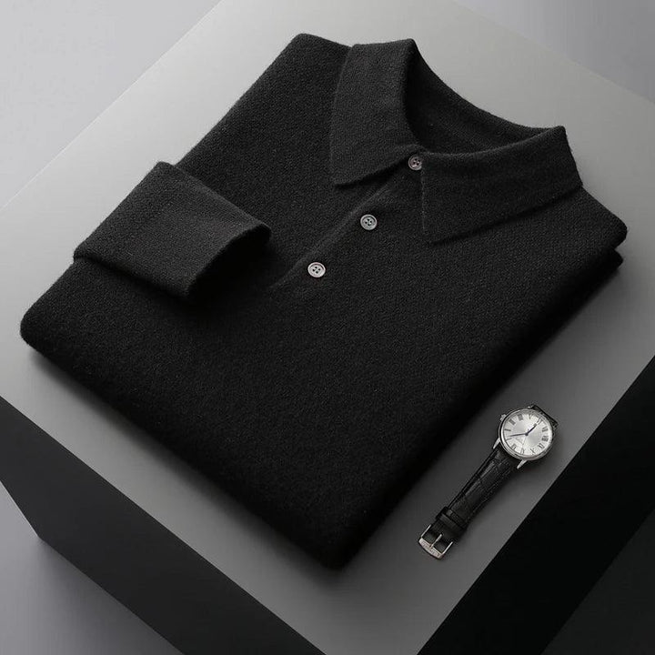 Folded black knit polo shirt with buttons and a silver wristwatch on a grey surface, Rovelli