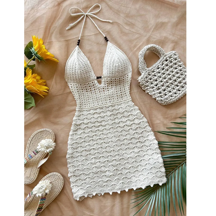 Crochet halter dress, matching bag, sandals, sunflowers, and palm leaf on neutral background, Rovelli fashion