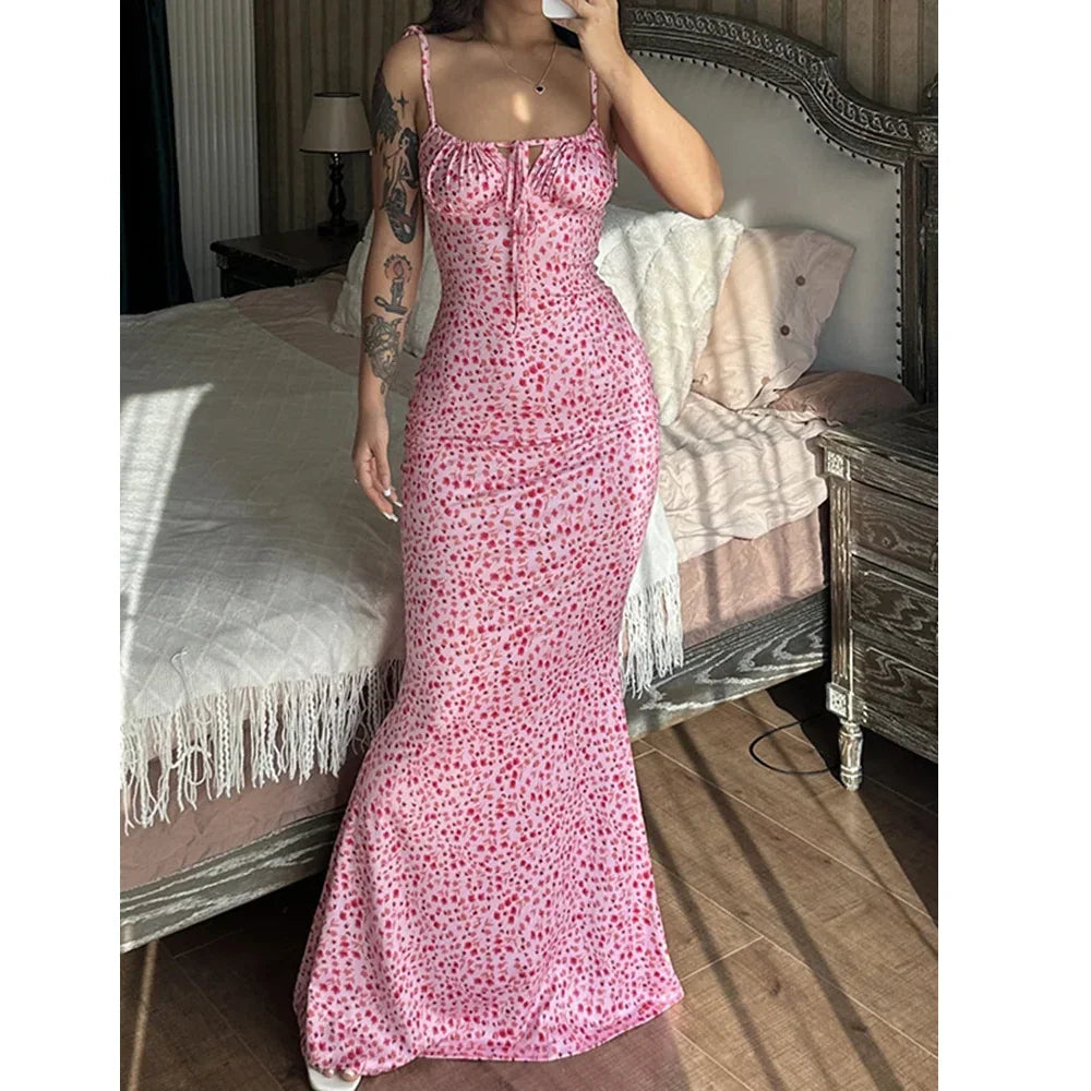 Woman wearing a pink floral maxi dress with thin straps, photographed in a stylish bedroom, Rovelli fashion.