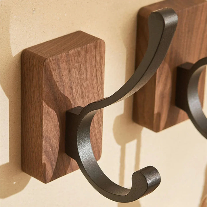 Rovelli modern wall hook with dark metal arm and wooden base on beige wall