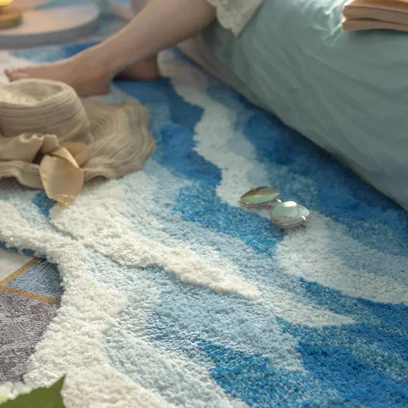 Soft blue and white area rug by Rovelli with hat and sunglasses beside a bed