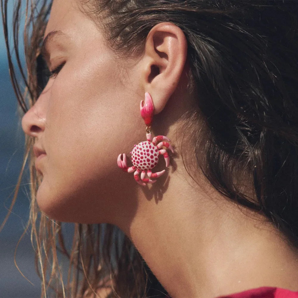 Woman wearing a pink crab-shaped statement earring, close-up, Rovelli jewelry style