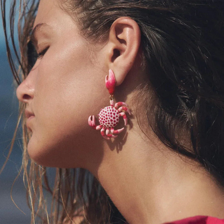 Woman wearing a pink crab-shaped statement earring, close-up, Rovelli jewelry style