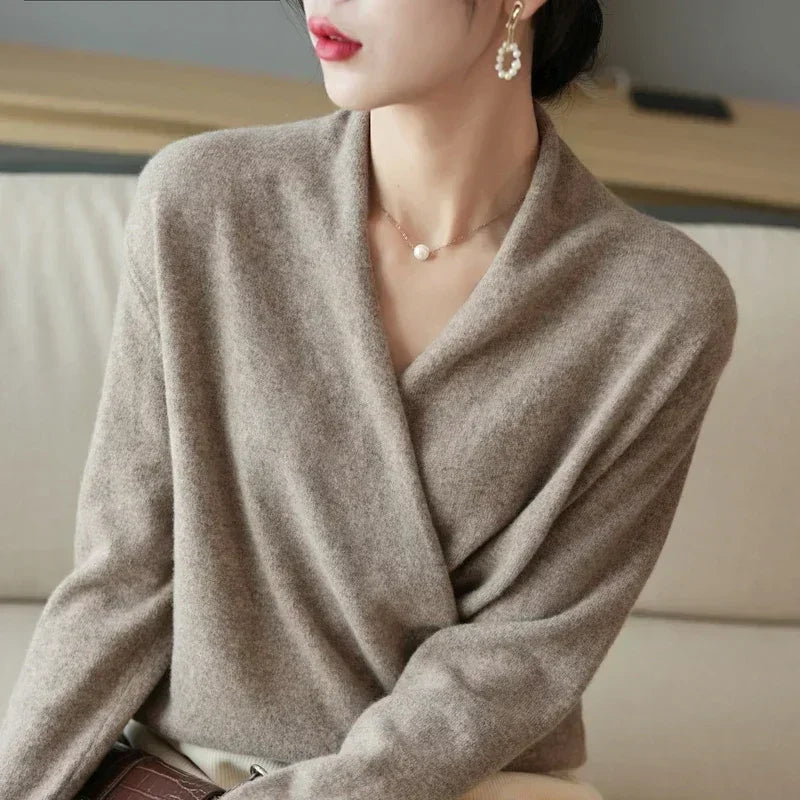 Woman wearing a soft beige wrap sweater, pearl earrings, and a delicate necklace, Rovelli style