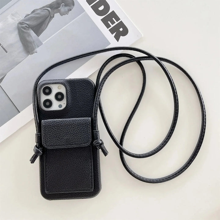 A black leather phone case with a small front pouch and a detachable lanyard rests atop a magazine featuring a grayscale photo of a person in a coat.