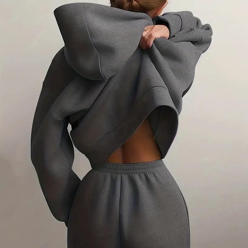 Back view of a woman in gray Rovelli hoodie and joggers, adjusting her sweatshirt.