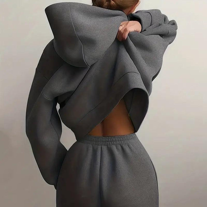 Back view of a woman in gray Rovelli hoodie and joggers, adjusting her sweatshirt.