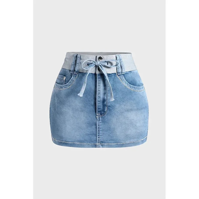 A light blue high waist denim skirt crafted from premium cotton, featuring a wide waistband, front pockets, button closure, and a matching denim tie belt, displayed against a plain white background.