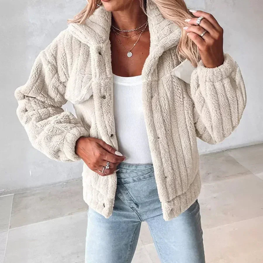 Woman wearing a cream sherpa jacket, white top, and light blue jeans by Rovelli