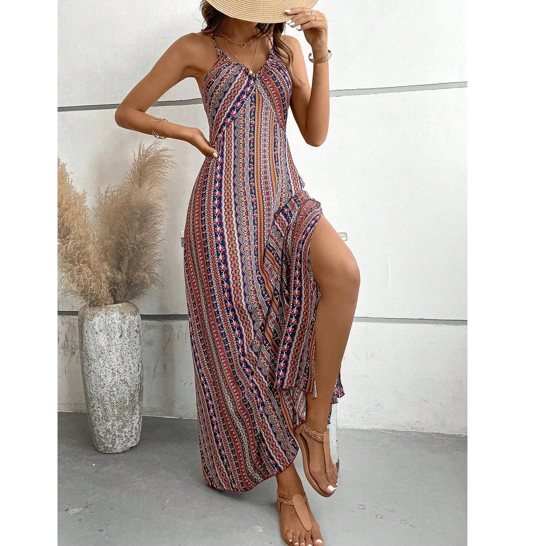 Woman wearing a colorful bohemian maxi dress and straw hat, standing indoors by a vase.