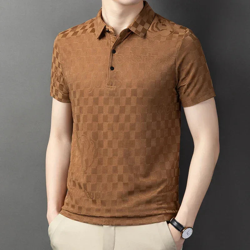 A person wearing a tailored fit, short-sleeve, brown checkerboard pattern polo shirt with a collar and three buttons, paired with light beige pants and a black watch, standing against a plain gray background.