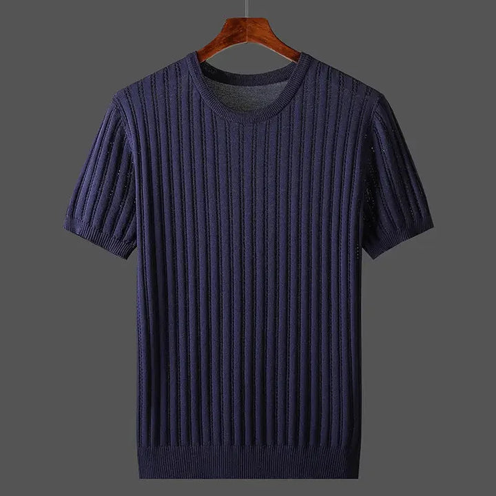A navy blue, short-sleeved, ribbed knit sweater in a classic fit hangs on a wooden hanger against a plain gray background.