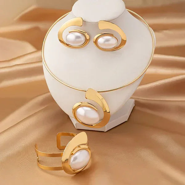 Rovelli gold jewelry set with pearl earrings, ring, and bracelet on satin background