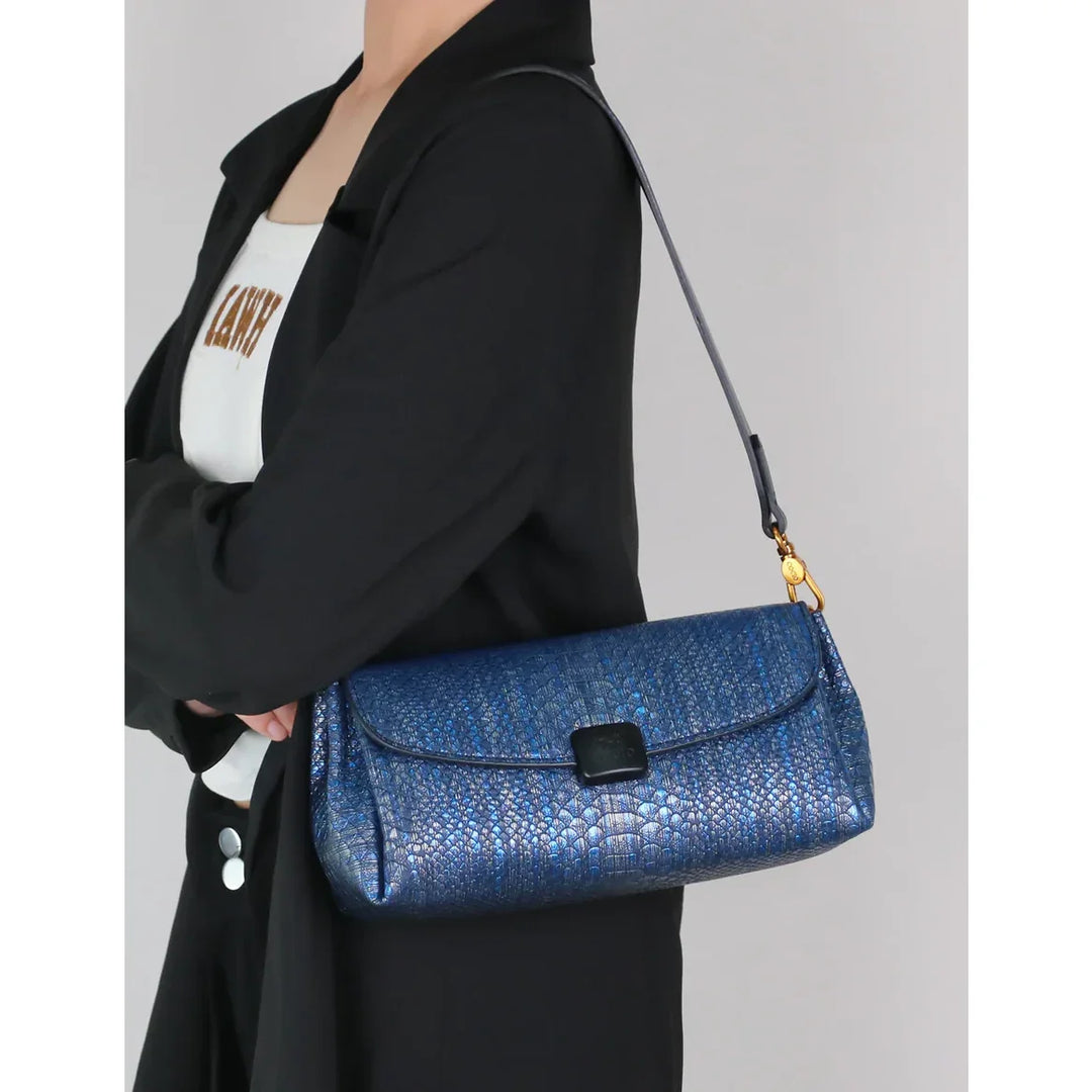 Woman wearing black blazer holding Rovelli blue textured shoulder bag