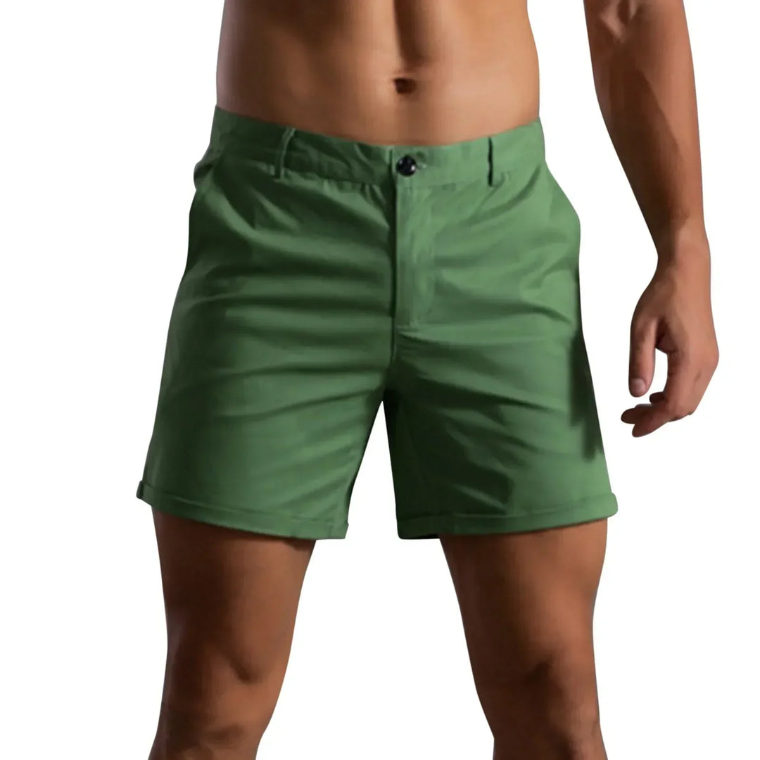 A person wearing green shorts with a tailored fit and semi elastic waistband, standing against a plain white background. The image focuses on the shorts and lower torso, with the head and lower legs not visible.