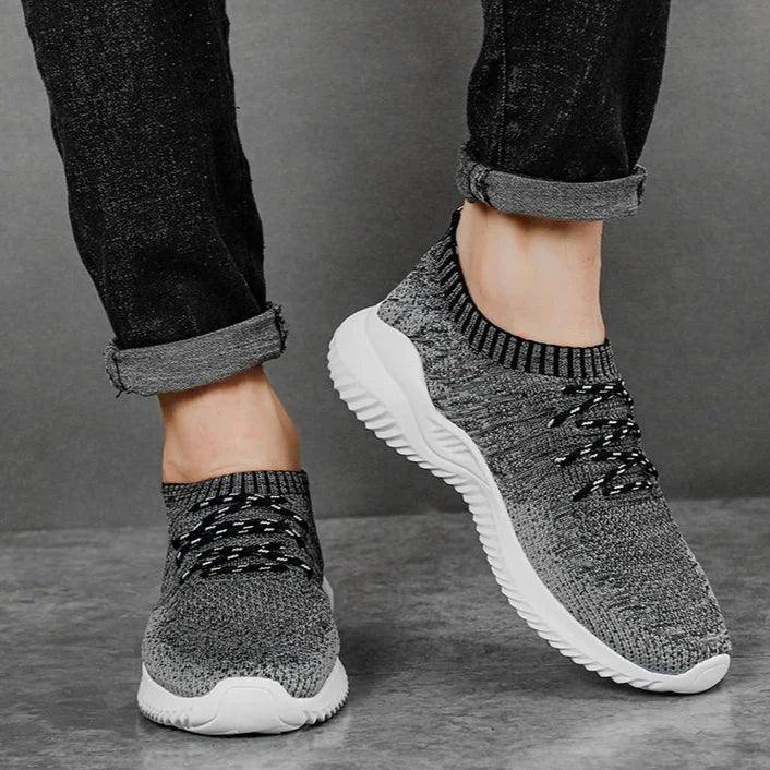 Rovelli gray knit sneakers with white soles, worn with rolled black jeans on gray floor