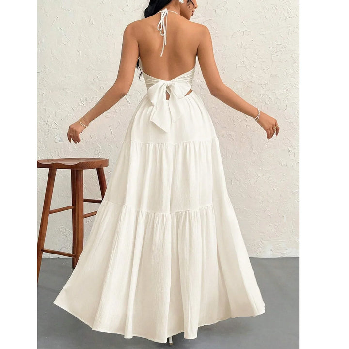 Woman wearing backless white maxi dress with bow, Rovelli fashion, neutral studio setting