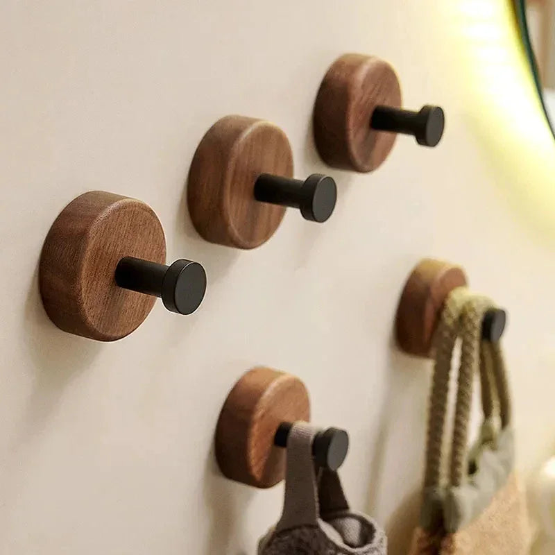 Modern wooden wall hooks with black pegs, organized on a beige wall, Rovelli home decor