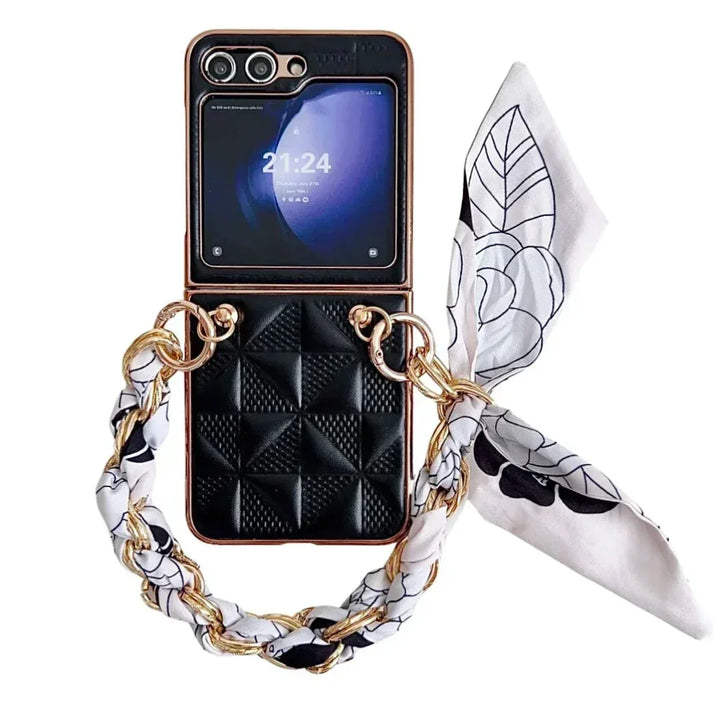 A Samsung Galaxy Z Flip in a black, quilted premium leather case with shockproof protection, gold chain, and white patterned scarf attached, displayed on a white background. The phone screen shows the time as 21:24.