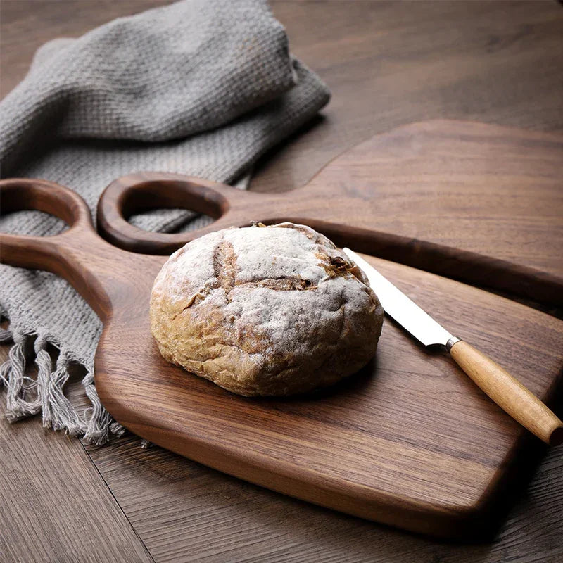 Rustic bread loaf and knife on wooden Rovelli cutting board, cozy kitchen setting