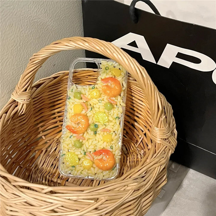 A phone case with 3D detailing, designed to look like a dish of fried rice with shrimp, peas, corn, and veggies sits in a woven wicker basket next to a black shopping bag.