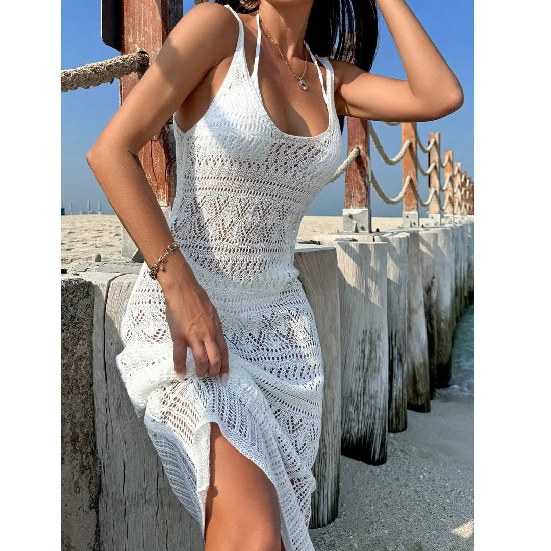 Woman wearing white crochet beach dress by wooden pier on sandy shore, Rovelli fashion