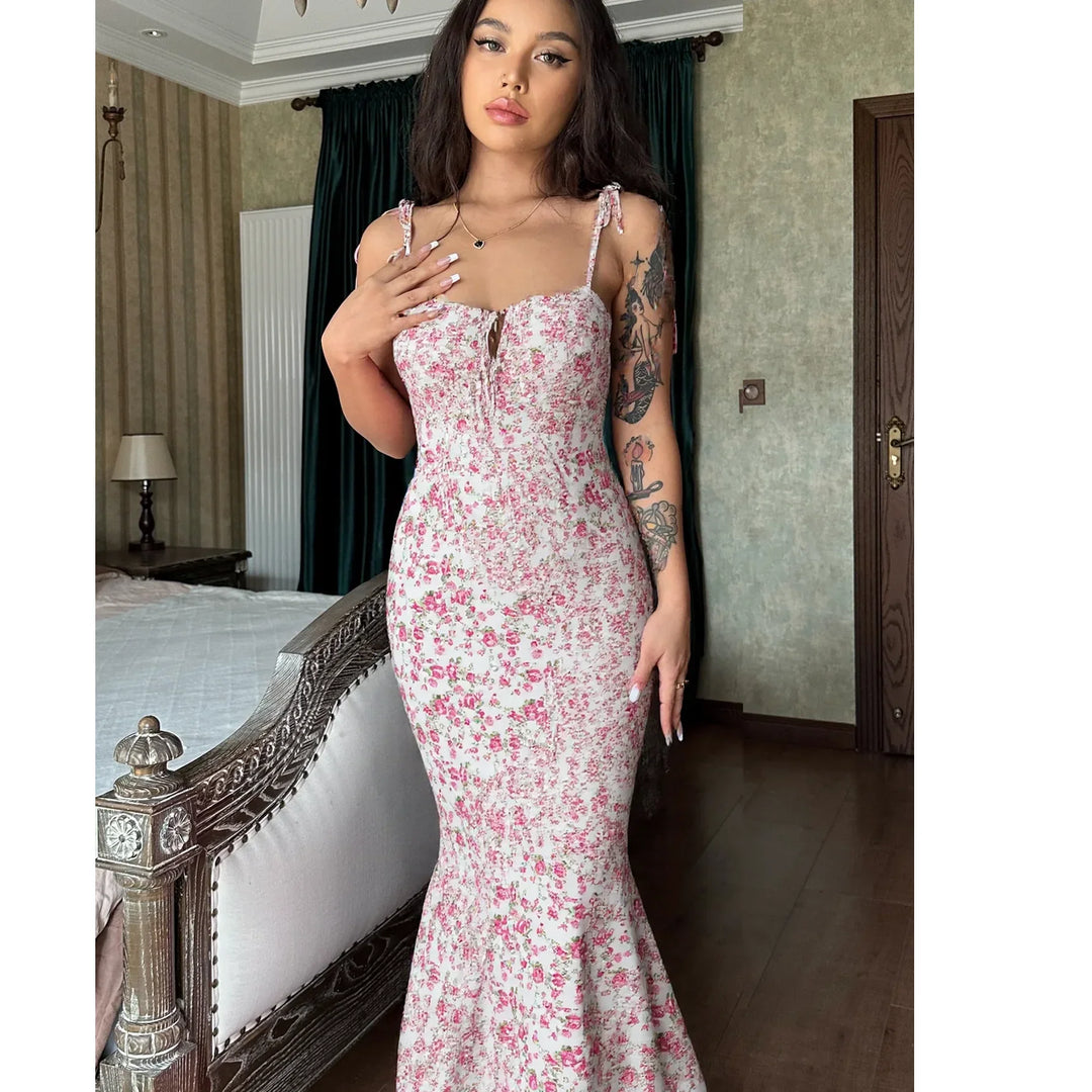 Woman in elegant pink floral dress standing in bedroom, Rovelli fashion style