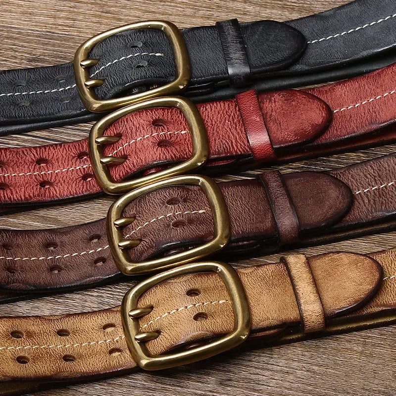 Four genuine leather belts in black, red, brown, and tan, each featuring a classic brass buckle, showcase heritage craftsmanship as they are laid out side by side on a wooden surface.