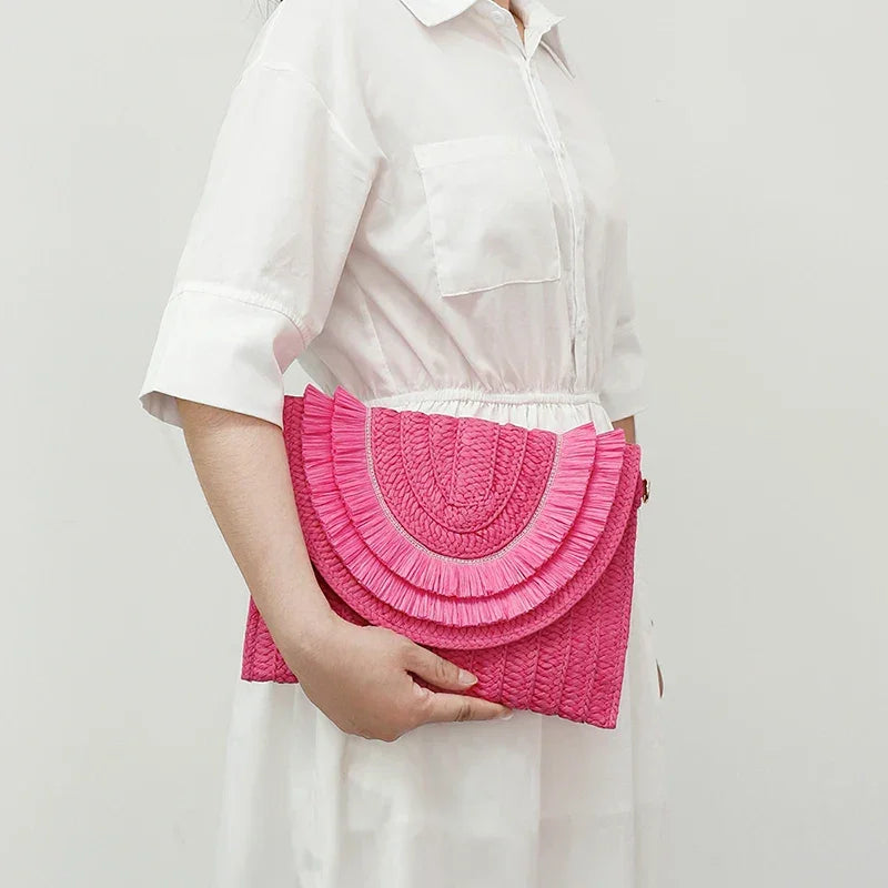 Woman in white dress holding a pink woven Rovelli clutch bag with textured semicircle design