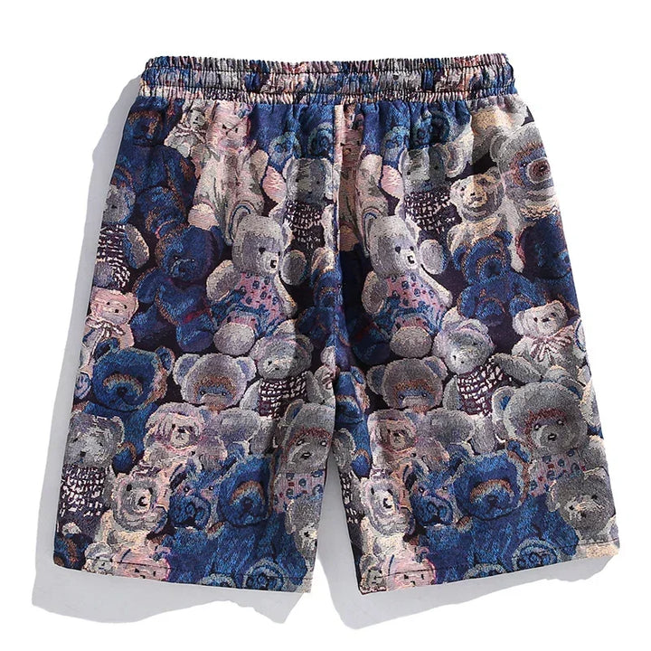 A pair of premium quality shorts with an elastic waistband, featuring a colorful, textured pattern of teddy bears in shades of blue, pink, and beige.