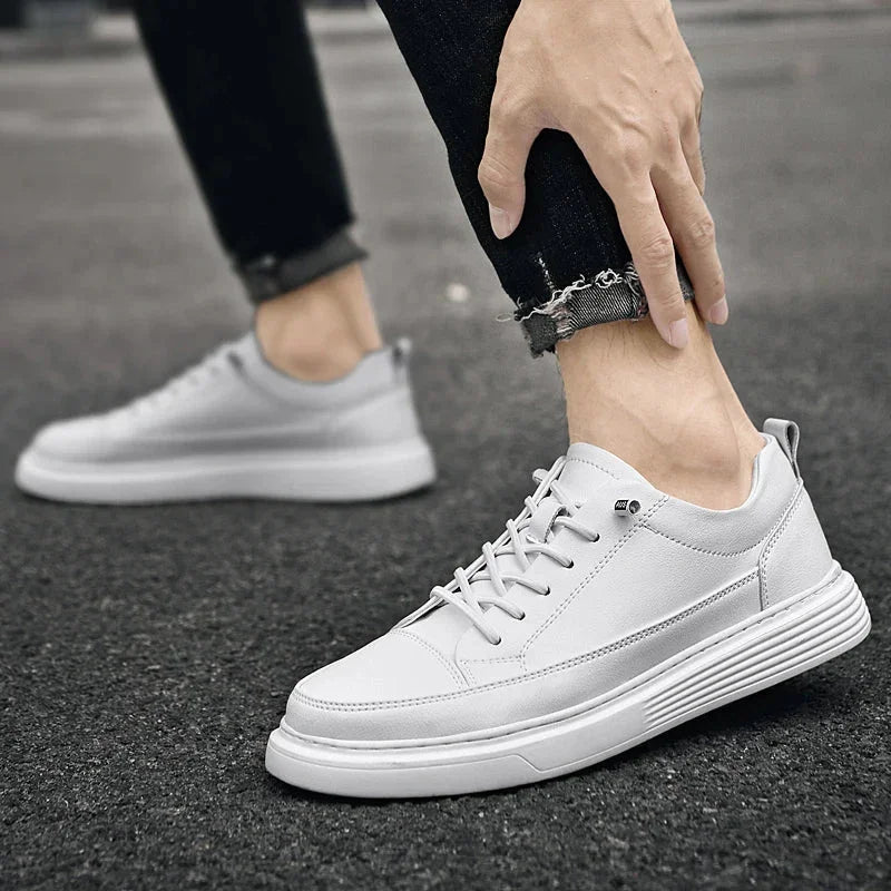 A person wearing white sneakers with RunForm insoles and black, slightly frayed jeans is adjusting one shoe while standing on a dark, textured pavement. The background is blurred.