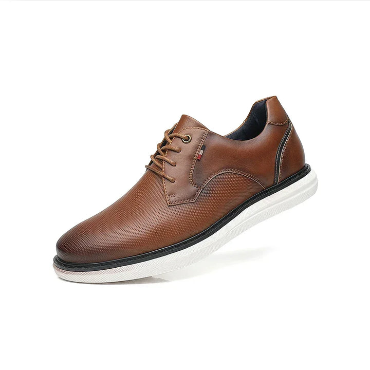 A single brown genuine leather oxford dress shoe with traditional detailing, white sole, and black trim, displayed against a plain white background.