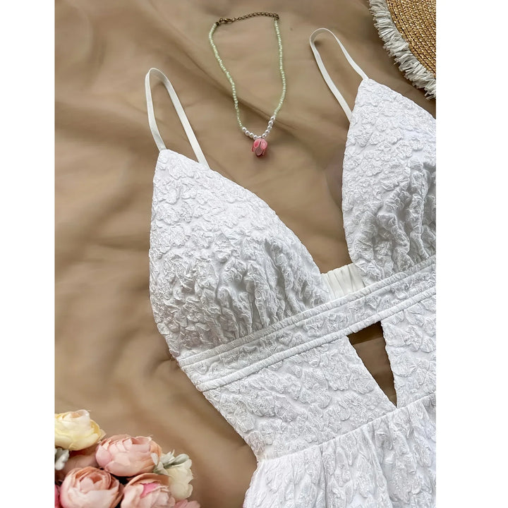 Rovelli white lace textured dress with thin straps, floral necklace, and roses on beige fabric