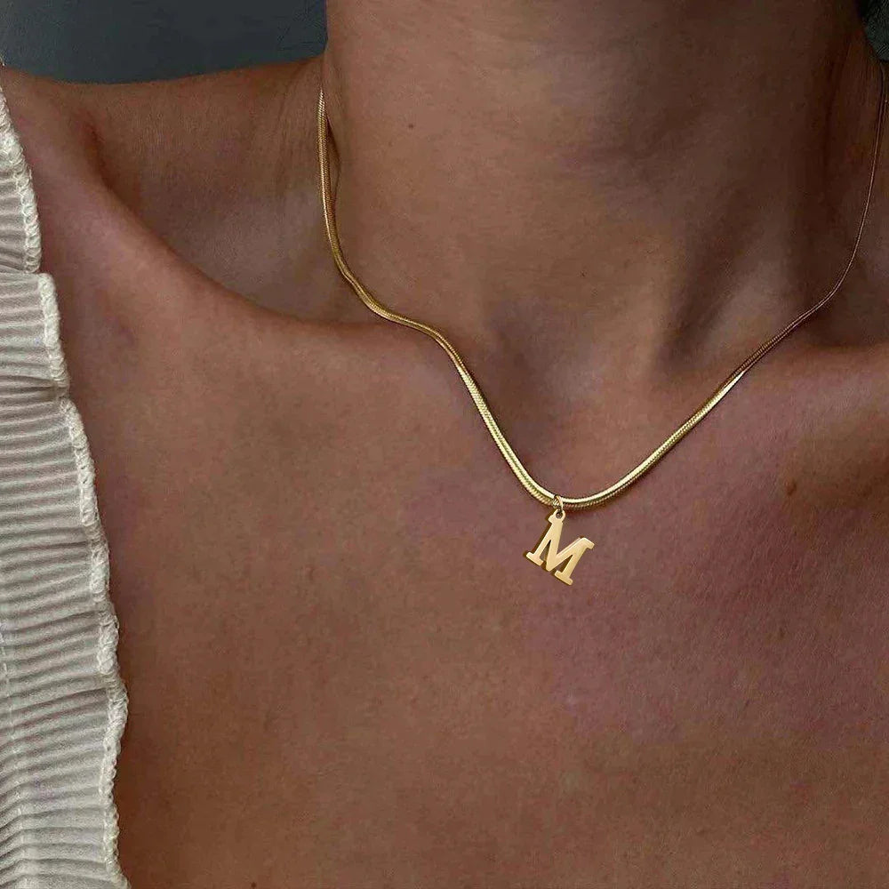 Gold initial M necklace on model's neck, featured jewelry from Rovelli