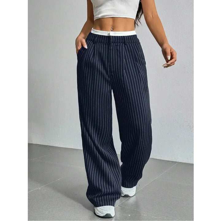 Woman wearing navy pinstripe wide-leg pants, white crop top, and sneakers, Rovelli fashion
