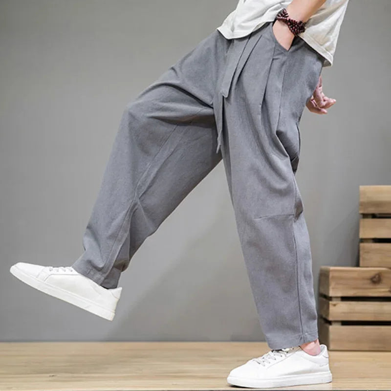 Rovelli loose fit gray pants with pleats, model in white sneakers, modern casual style