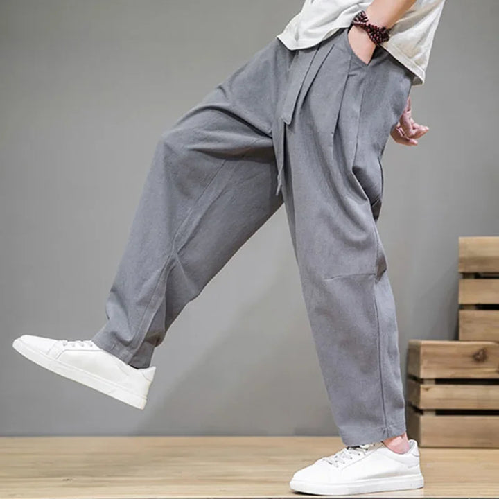 Rovelli loose fit gray pants with pleats, model in white sneakers, modern casual style