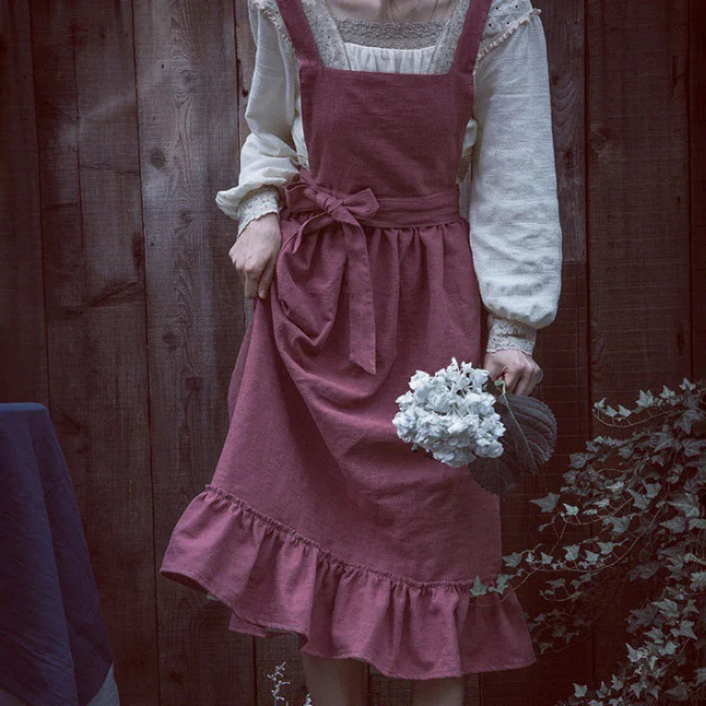 Woman in vintage pink pinafore dress holding white flowers, rustic wood background, Rovelli fashion