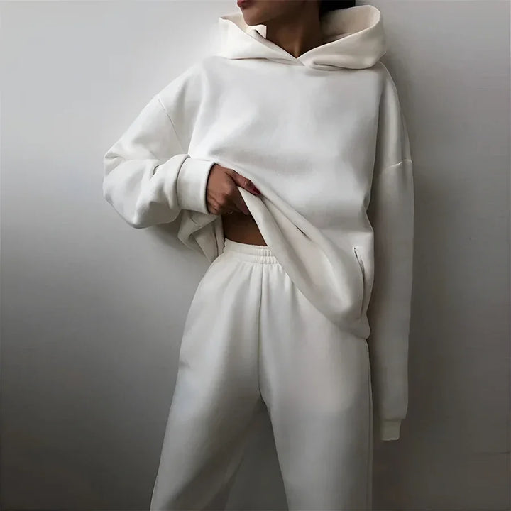 Woman wearing off-white Rovelli hoodie and sweatpants set against a plain background