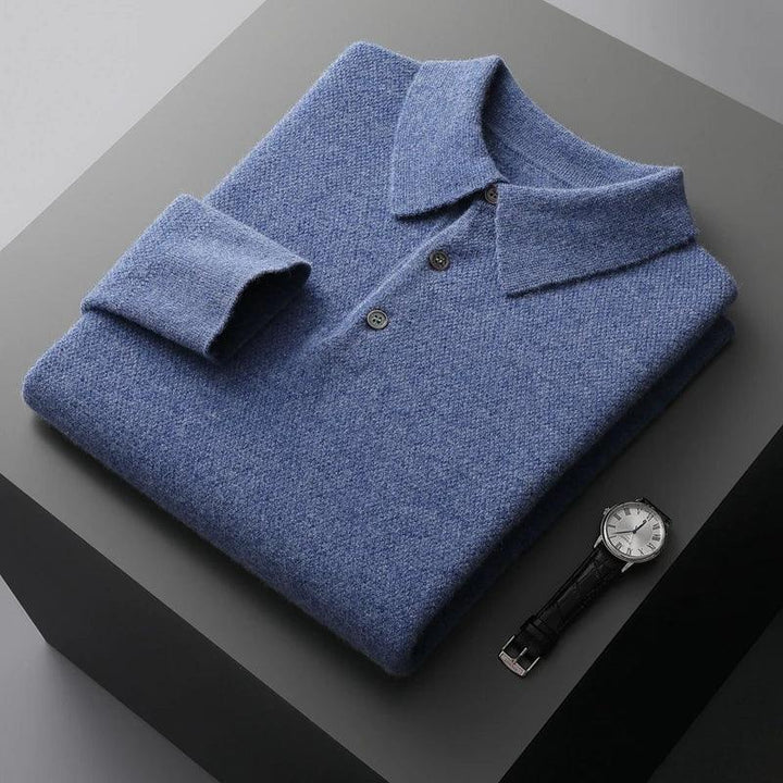 Folded blue knit polo sweater with buttons beside a wristwatch on a gray surface, Rovelli