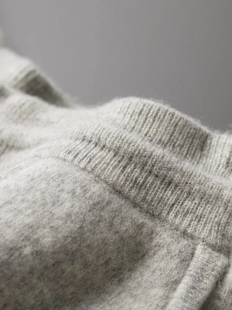 Close-up of a soft, light gray knitted fabric with ribbed waistband and seam details, highlighting comfortable pants made from durable construction—ideal for cozy loungewear like Merino wool pants against a neutral background.